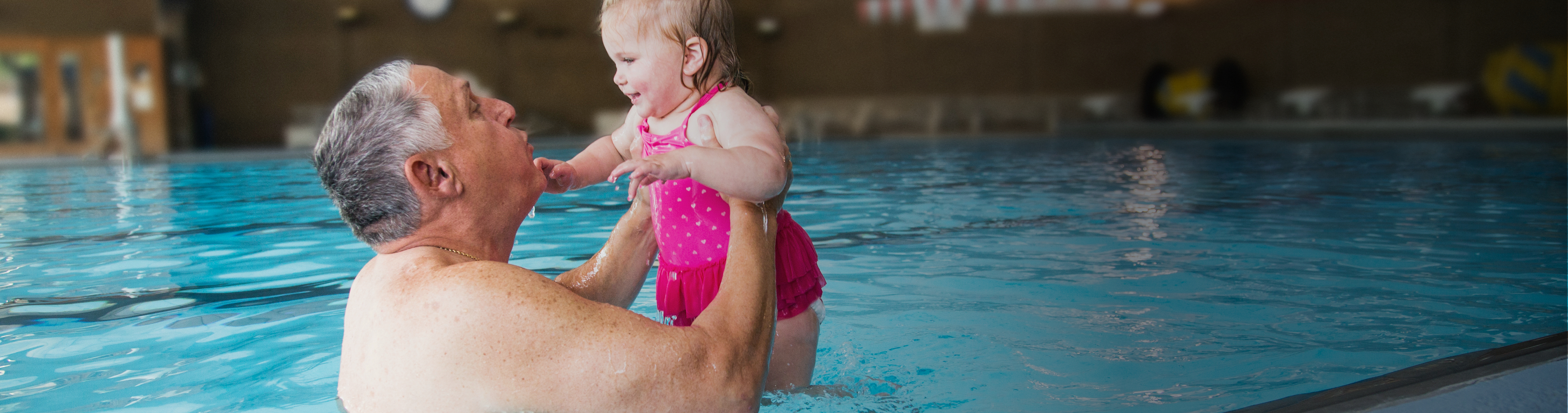 Grandfather playing in the pool with his granddaughter