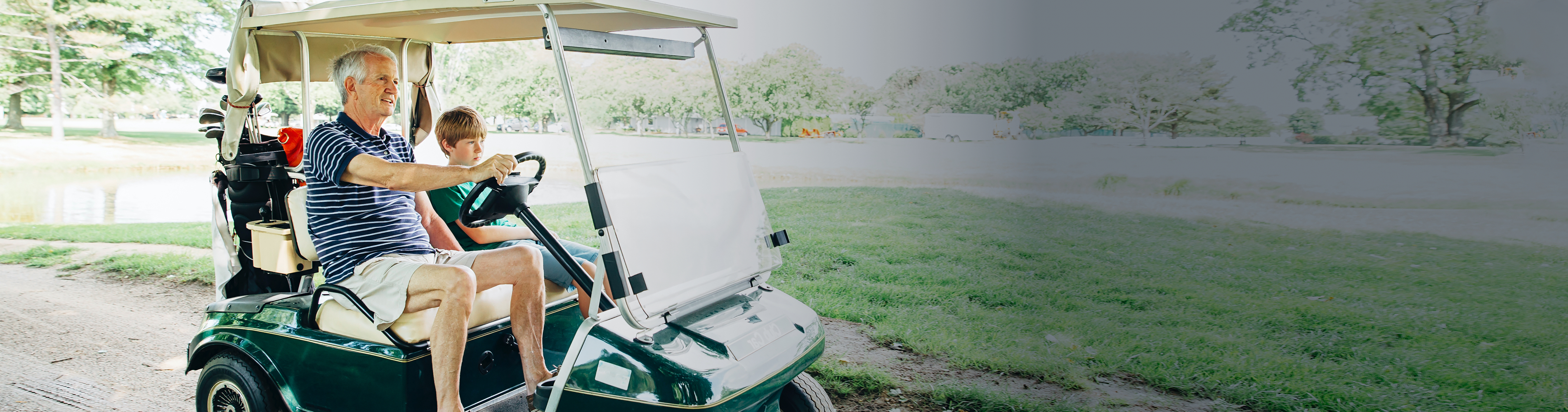 Senior man driving golf cart with his grandson