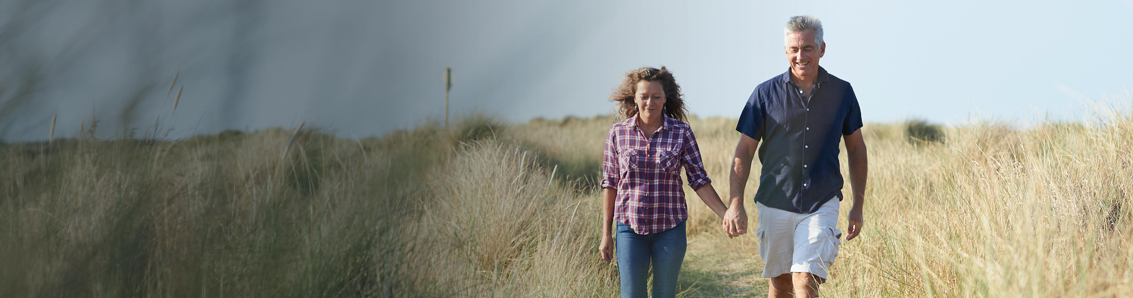 Couple walking through a field of tall grasses